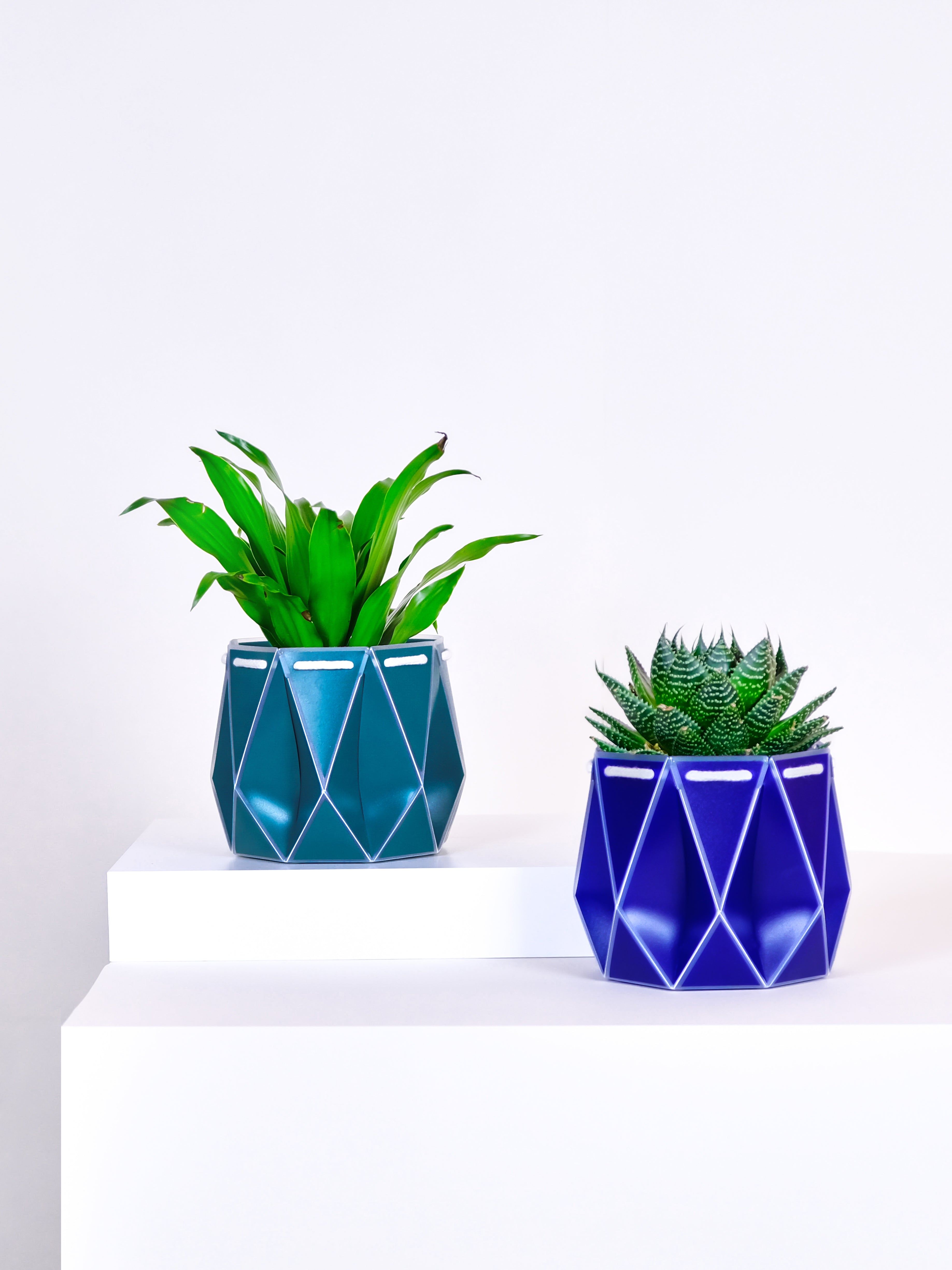 11cm origami self-watering plant pots in green and blue colours. Made from recycled single use plastic.