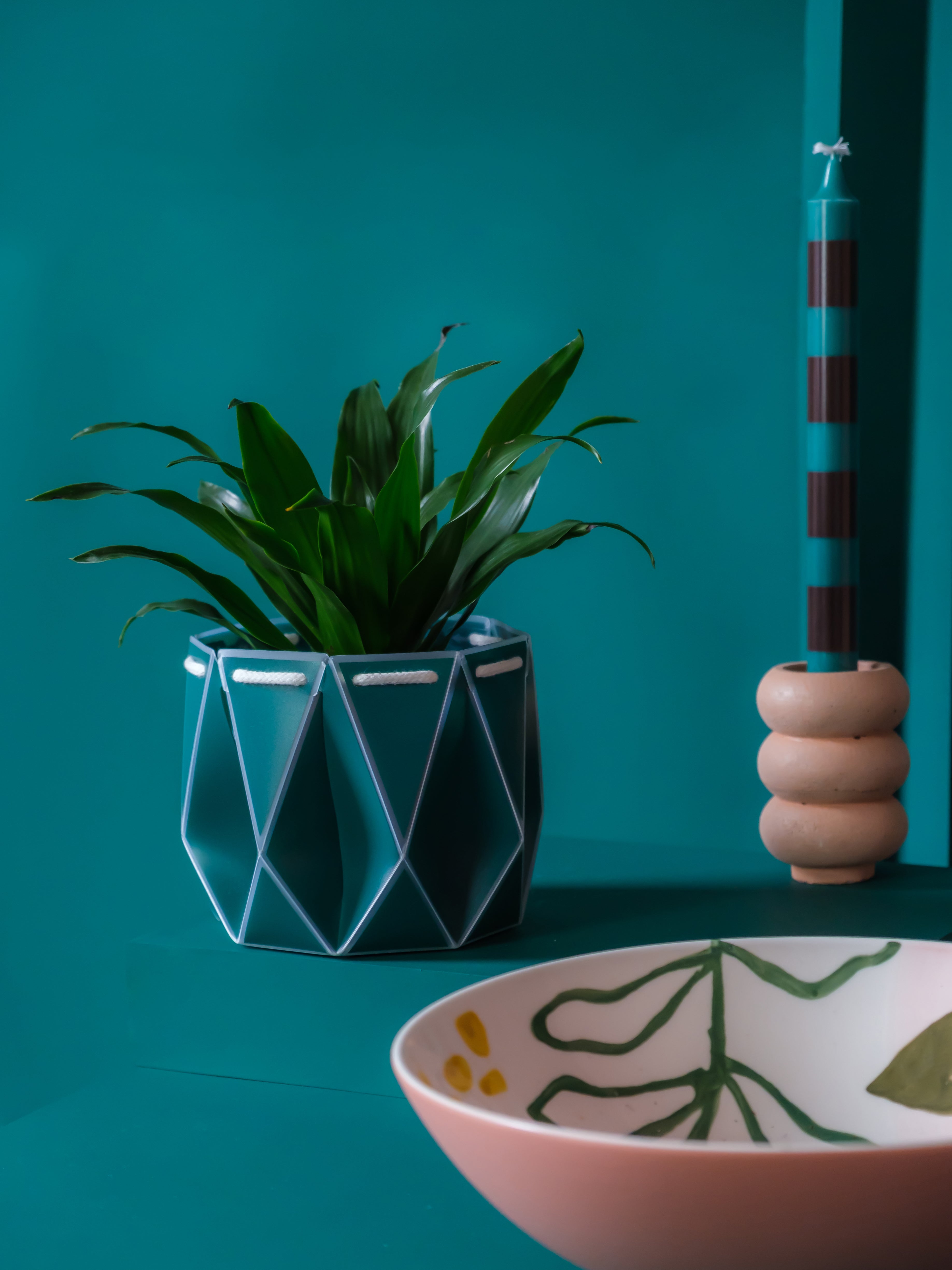 Origami planter which is self-watering for your plants. Arranged with a bowl and candle.